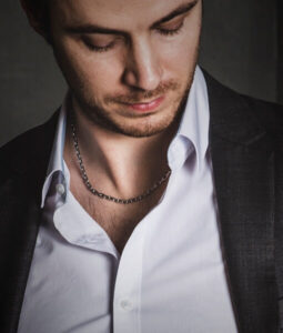 CHAIN NECKLACE UNDER A SHIRT WITH FIRST BUTTON OPEN